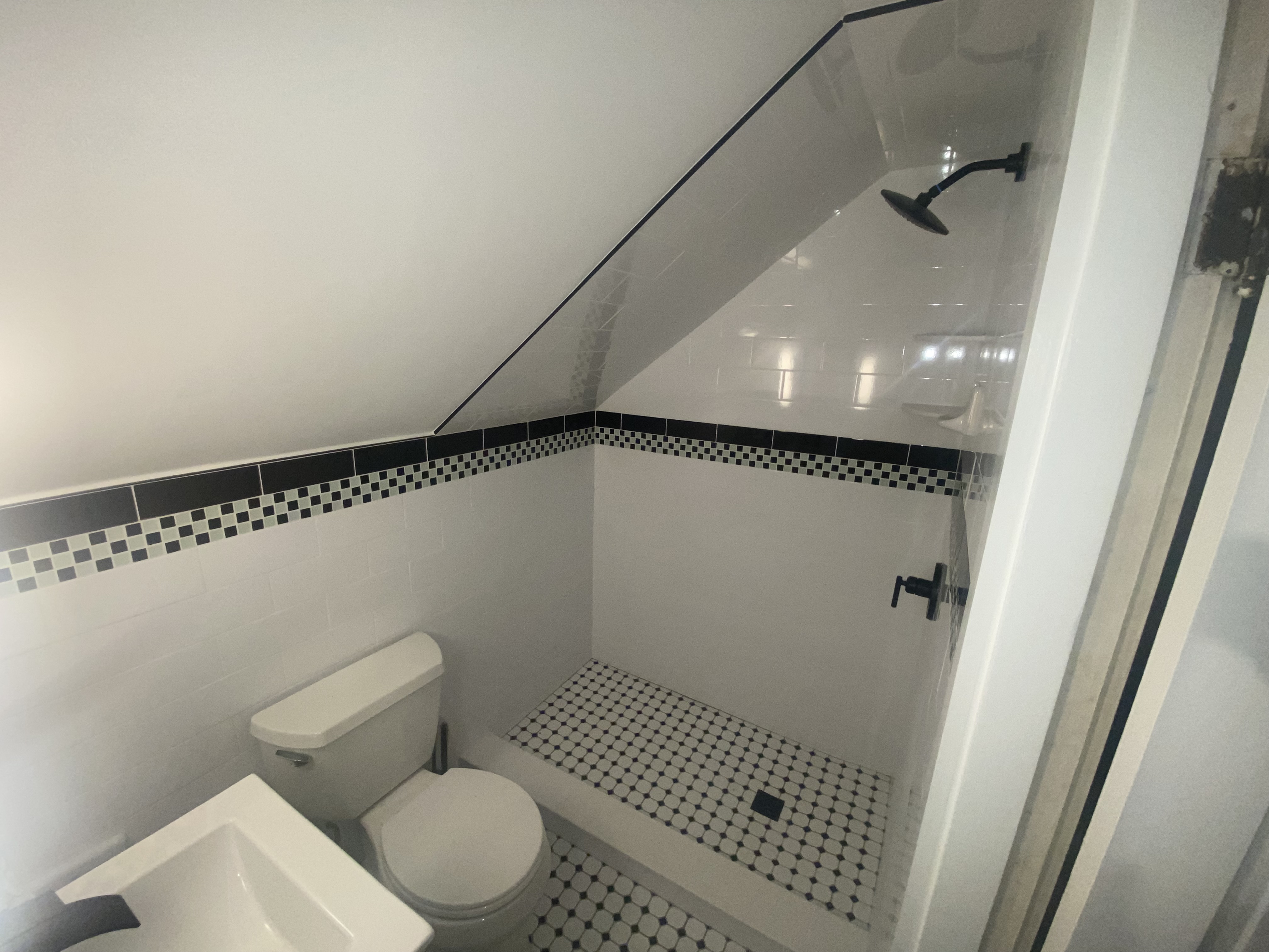 Bathroom renovation with white subway tile, checkerboard mosaic border, and octagon dot tile floor by Bulldog Construction