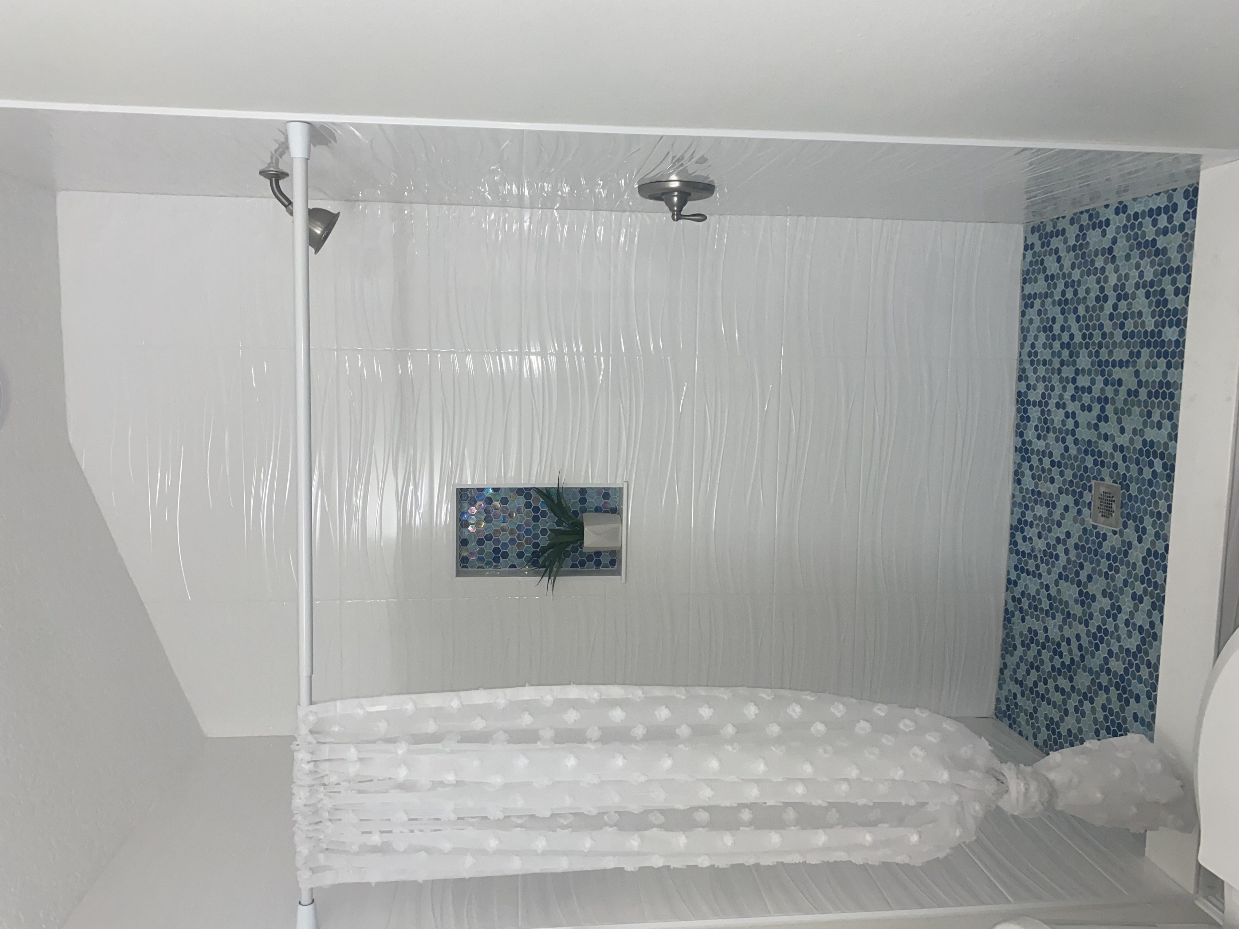 Walk-in shower renovation with white textured wall tile and blue hexagon mosaic floor by Bulldog Construction