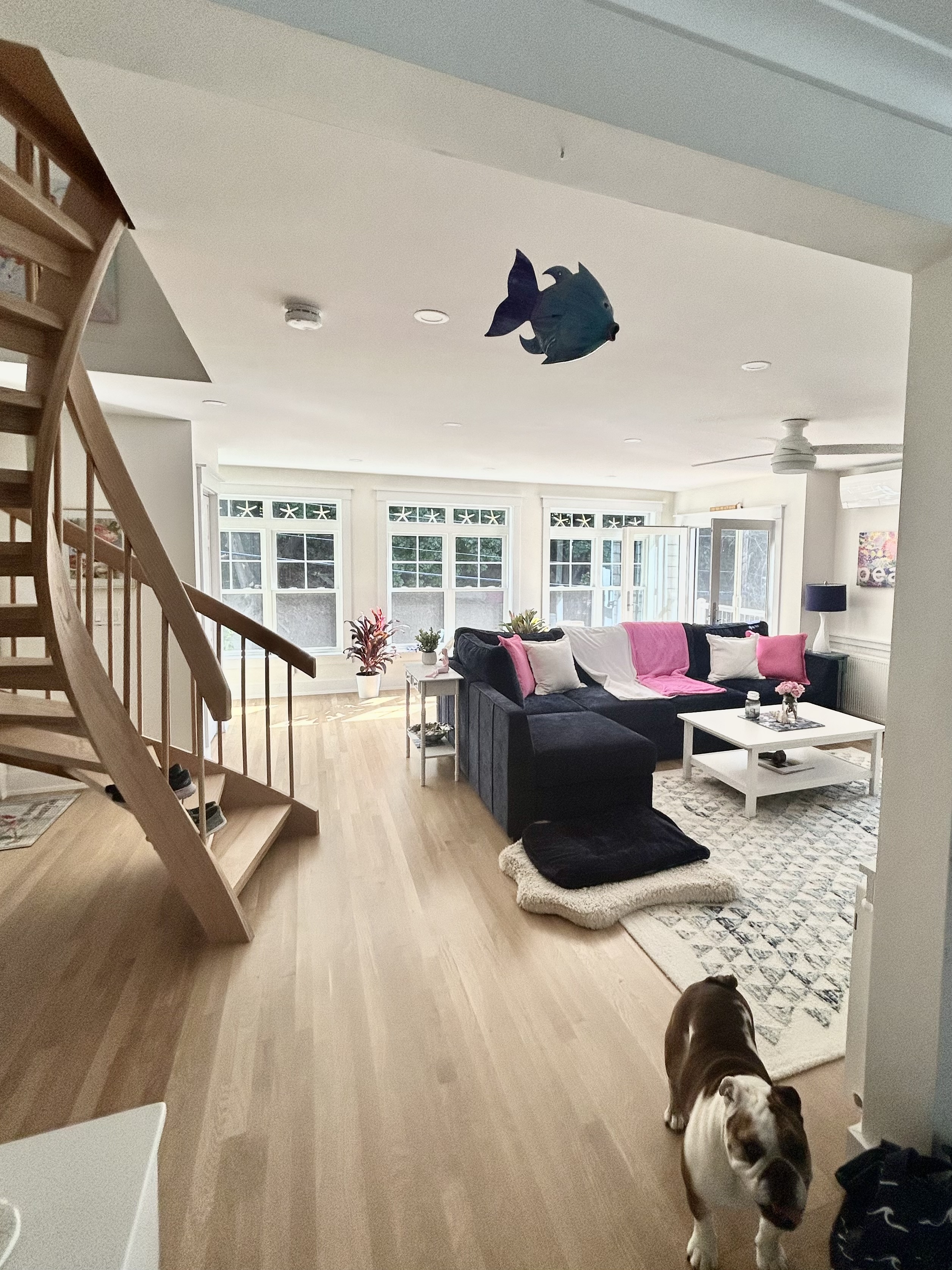 Open-concept living area renovation with curved staircase by Bulldog Construction