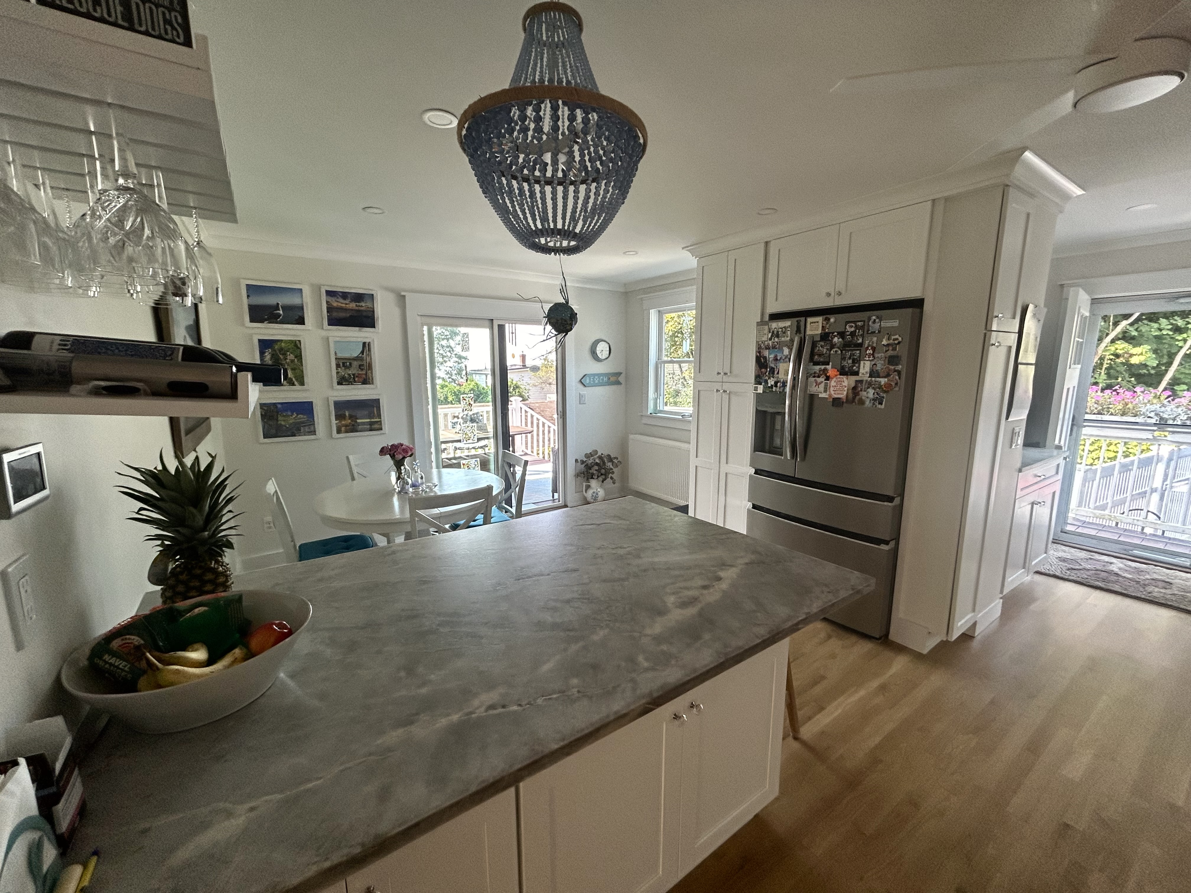 Bright open-concept white kitchen with large island and stainless appliances by Bulldog Construction