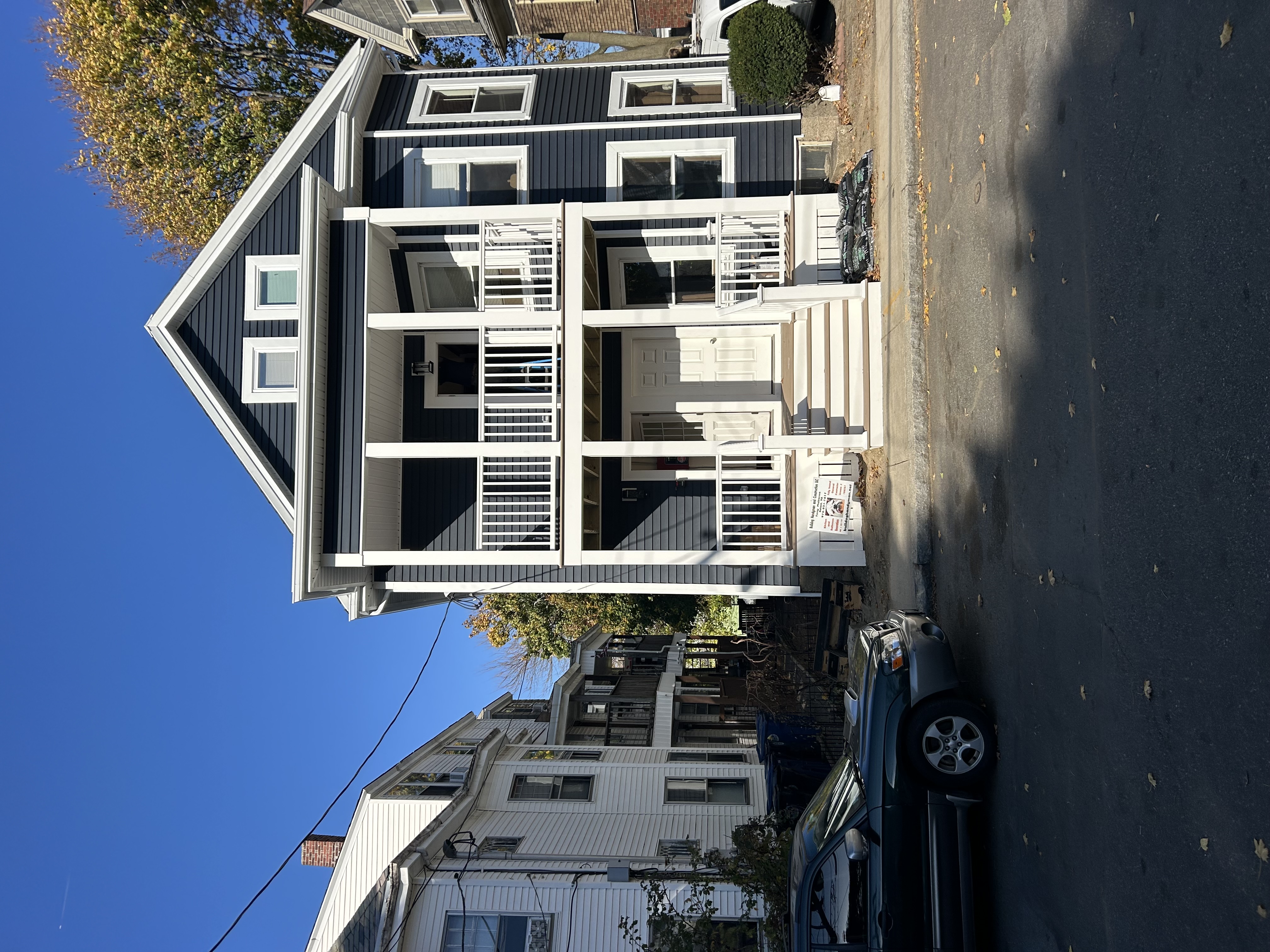Renovated home with dark navy siding, white trim, and a two-story white porch after the exterior renovation by Bulldog Construction
