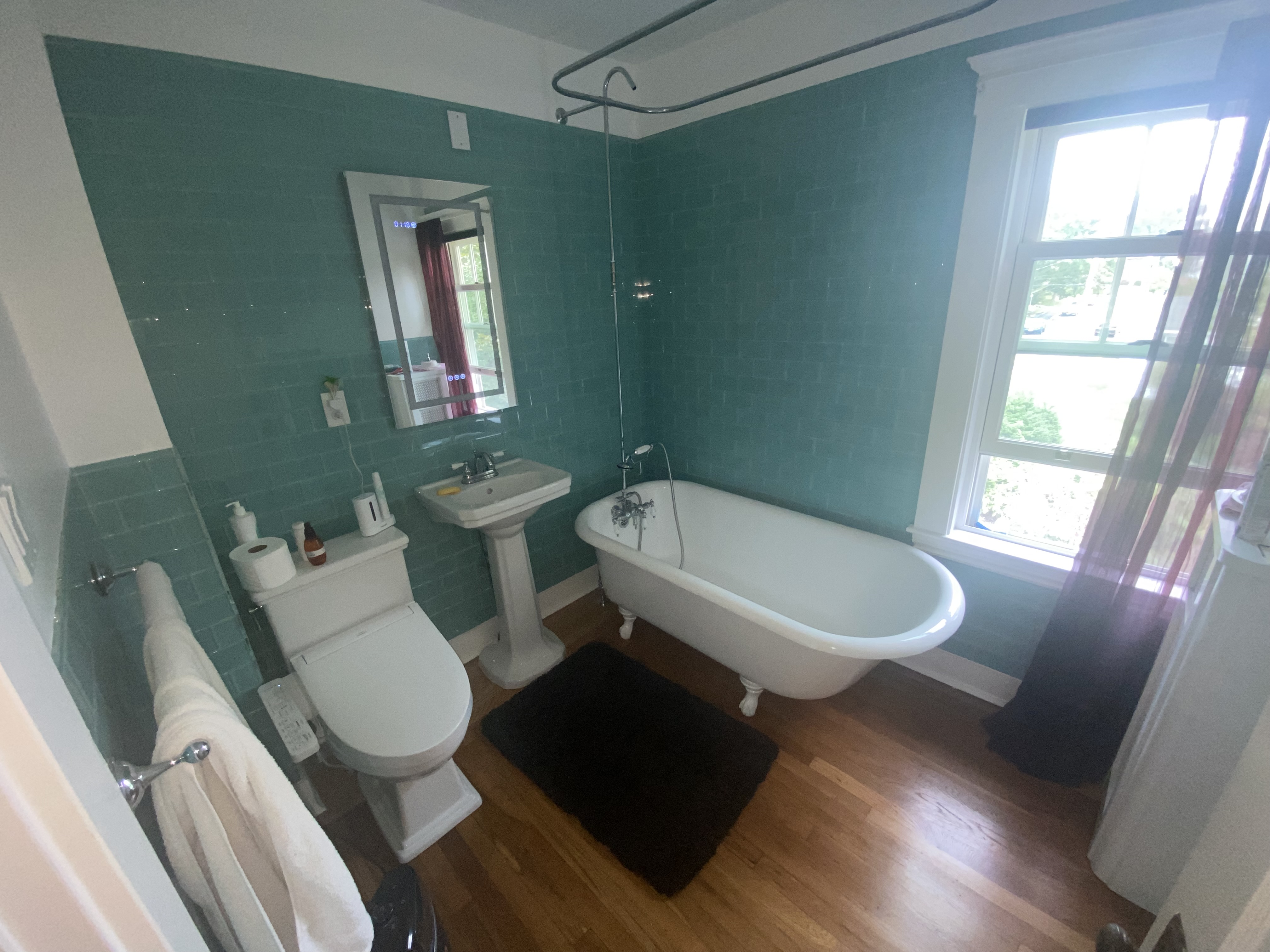 Bathroom renovation with teal subway tile, clawfoot soaking tub, and pedestal sink by Bulldog Construction